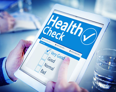 A man is holding a smart tablet that has a Health Check Wellness Screening on it