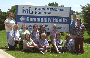 The Horn Home Health Department group is standing outside, in front of the Hospital sign, smiling