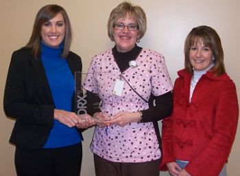 Three females standing next to each other, holding a Leadership Award from Carestream Health and Cassling