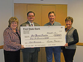 The HMH Foundation for Digital Mammography holding a donation check of $25,000, that was given to them by First State Bank. There us two females and two males