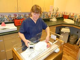 A female Nurse is performing a hearing screening on a newborn